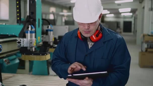 A male factory worker uses a tablet in the workshop. — Stock video