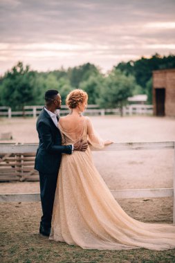 İki aşık erkek ve kadın gün batımında bir çiftlikte kucaklayan standı