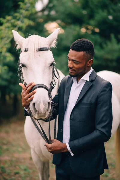 En ung afrikansk man smeker en häst. — Stockfoto