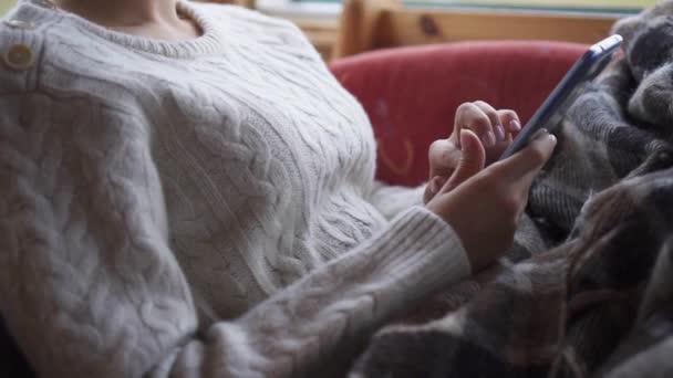 Une femme utilise un smartphone sur le canapé à la maison .