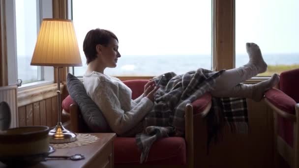 Bir kadın evdeki kanepede akıllı telefon kullanıyor.. — Stok video