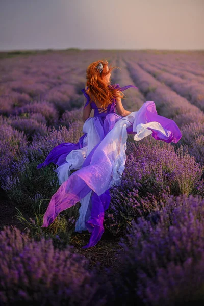 ラベンダー畑に沿ってドレスを着た女性が走っています. — ストック写真