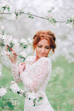 Portrait of a red-haired woman in white blossom.