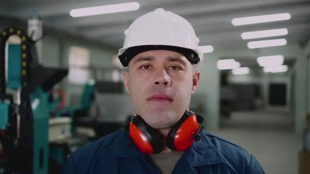 En mandlig fabriksarbejder kigger på kameraet, nærbillede . – Stock-video