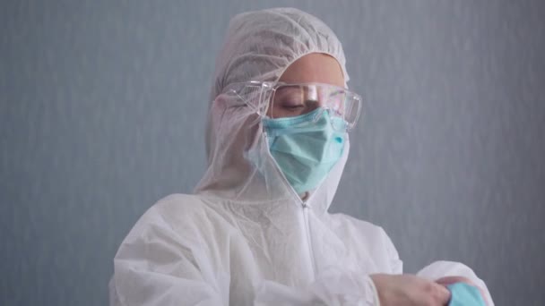 Medic in een beschermend pak trekt handschoenen aan. — Stockvideo