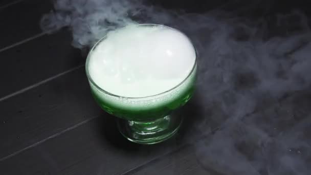 Liquide vert ébullition dégageant de la fumée dans un bol en verre sur fond noir — Video