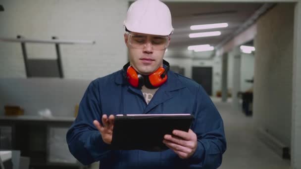 Um trabalhador da fábrica masculino usa um tablet na oficina . — Vídeo de Stock