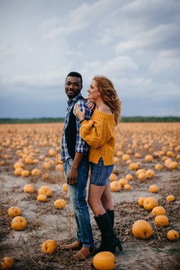 Balkabağı tarlasında duran genç bir çift çiftçi.