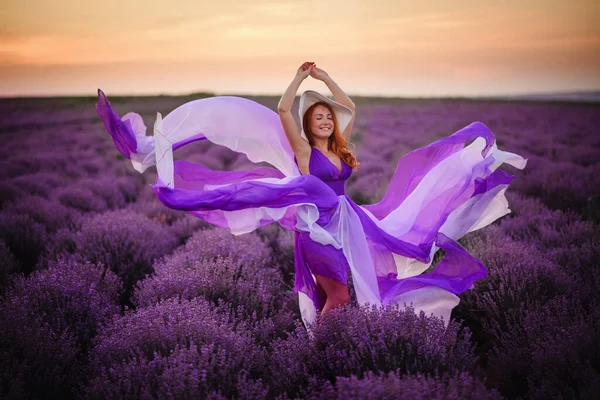 若いです幸せな女性で豪華な紫色のドレスに立ってラベンダー畑 — ストック写真