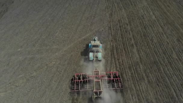 Un tracteur avec une herse cultive la terre . — Video