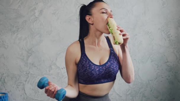 Mujer atlética comiendo comida chatarra . — Vídeos de Stock