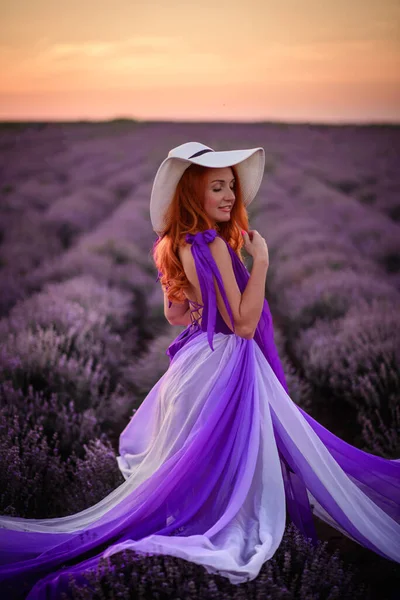 日没時にラベンダー畑に立つ豪華なドレス姿の幸せな赤い髪の女性 — ストック写真