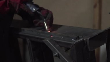 A welder is welding metal construction elements, close-up.