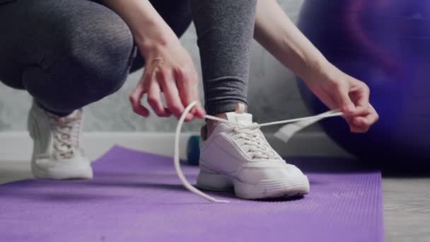 Женщина завязывает шнурки на кроссовках . — стоковое видео