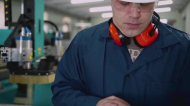 Bir erkek fabrika işçisi atölyede bir tablet kullanıyor..