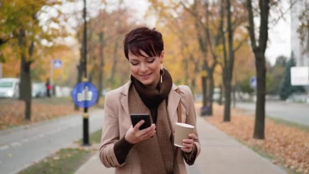 Eine Frau benutzt ihr Smartphone auf der Straße. — Stockvideo