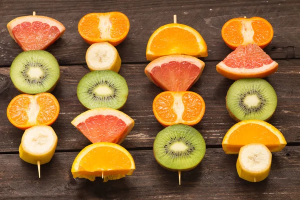 Espetos de frutas no fundo de madeira / o conceito de estilo de vida saudável — Fotografia de Stock