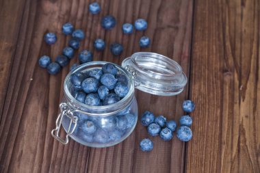 Ahşap bir masa üzerinde bir kavanoza yaban mersini