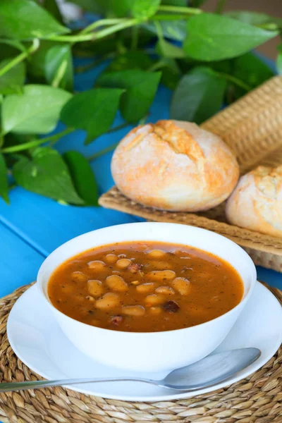 A zsemlét, a kék fából készült asztal bableves — Stock Fotó