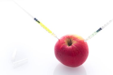 Delikli iğne ve şırınga ile elma yemek değiştirmek için bir kavram olarak / beyaz arka plan