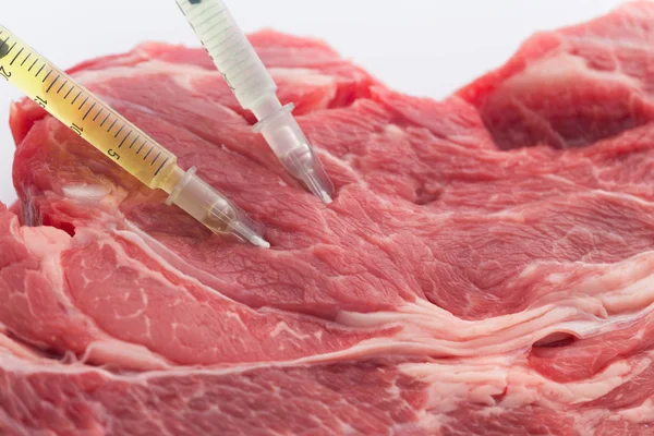Modified food. Beef meat with embedded syringes / concept