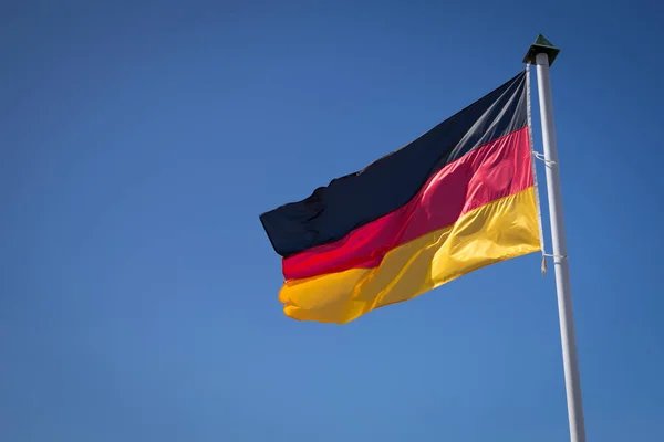 German flag waving against the blue sky