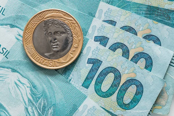 Brazilian Real coin and 100 Reais banknotes
