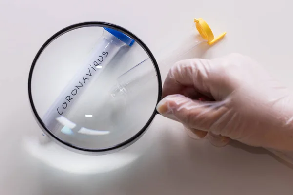 Coronovirus vial under a magnifying glass, The concept of research and finding a cure for a dangerous virus