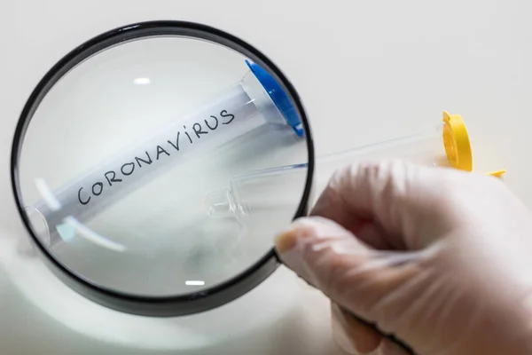 Coronovirus vial under a magnifying glass, The concept of research and finding a cure for a dangerous virus