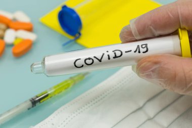 Covid-19 / Coronavirus resmi adı. Elinde laboratuvar eldiveni ve konsepti olan bir şişe.