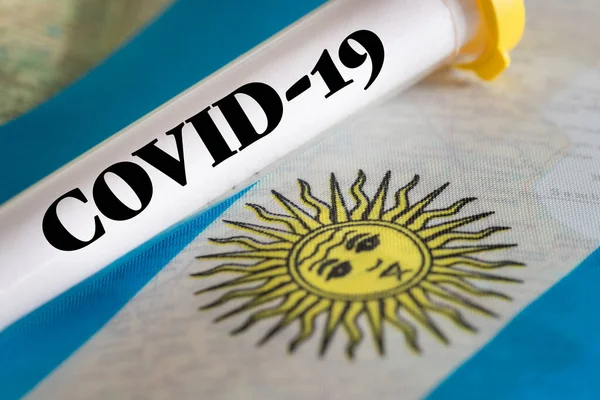test tube with a positive test for Coronavirus on the background of the Argentine flag