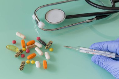  Doktorun elinde termometre, steteskop, ilaç. Tedavi kavramı