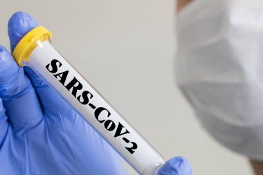 Elinde Coronavirus tüpü tutan koruyucu maskeli bir doktor.