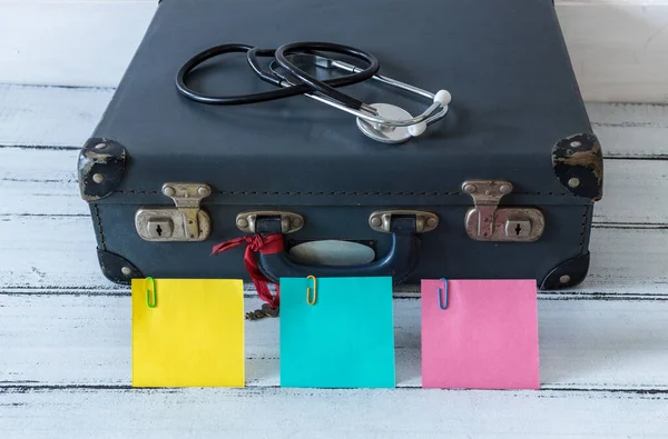 コンパスと医療用聴診器付きのレトロスタイルのスーツケース 碑文のためのスペースとカラフルな粘着性のあるノート パンデミックの間の安全な休日と家族旅行の概念 — ストック写真