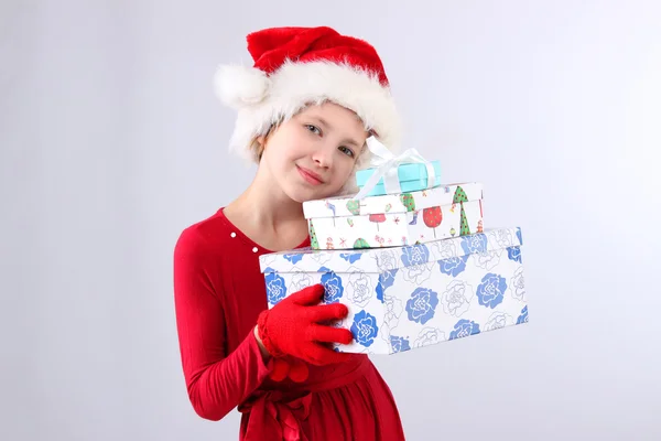 Портрет маленькой девочки в шляпе Санта-Помощника с цветными коробками подарков на светлом фоне — стоковое фото