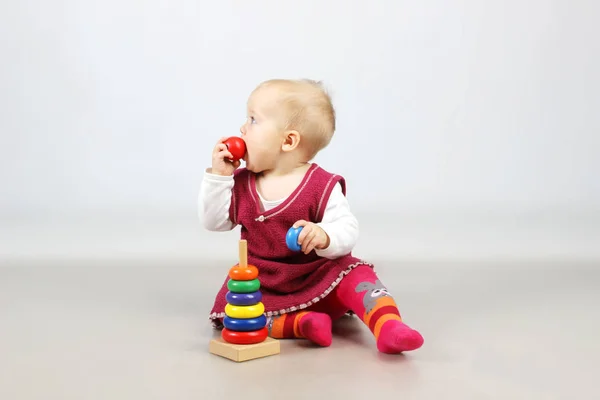 Bébé fille en robe rouge jouer avec des jouets . — Photo