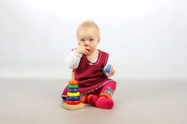 Bébé fille en robe rouge jouer avec des jouets . — Photo