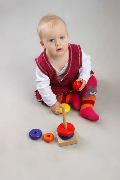 Entzückendes kleines Mädchen in roter Kleidung, das mit einigen Spielzeugen spielt. — Stockfoto