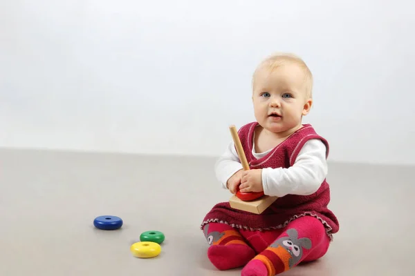 Adorable baby girl in red clothes playing with some toys. — Stock Photo, Image