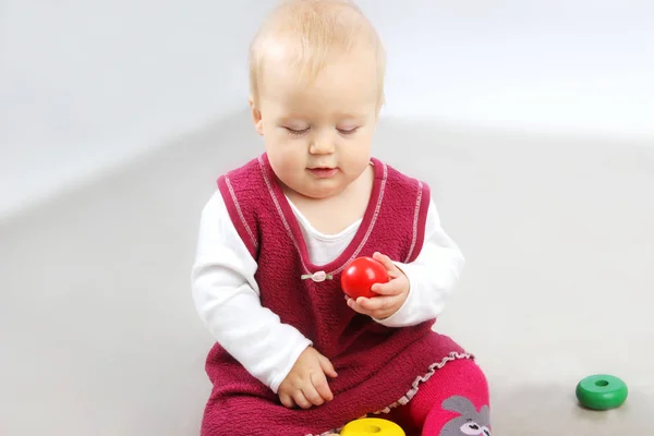 Adorable petite fille en vêtements rouges jouant avec des jouets . — Photo