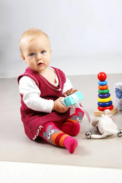 Entzückendes kleines Mädchen in roter Kleidung, das mit einigen Spielzeugen spielt. — Stockfoto