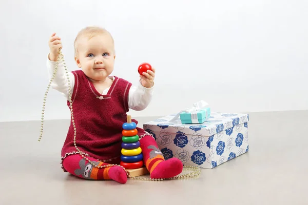 Tourné d'une petite adorable petite fille en robe rouge ouvrant des cadeaux et jouant des jouets . — Photo