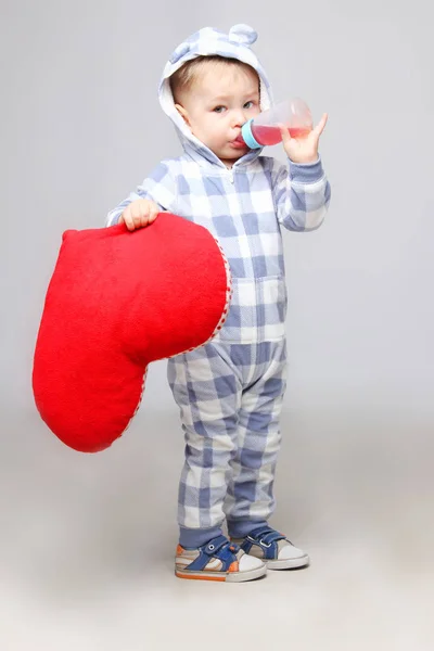 Porträt eines süßen kleinen Jungen, der ein herzförmiges Schild hält und einen Saft trinkt. — Stockfoto