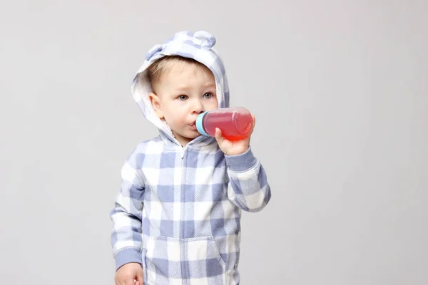 Schot van een kleine babyjongen drinken uit een sippy beker. — Stockfoto