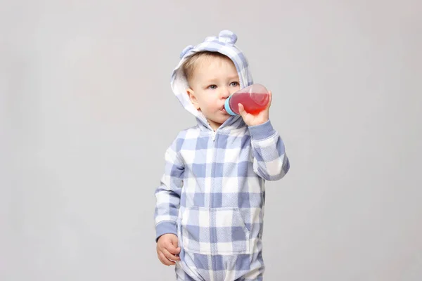 Schot van een kleine babyjongen drinken uit een sippy beker. — Stockfoto