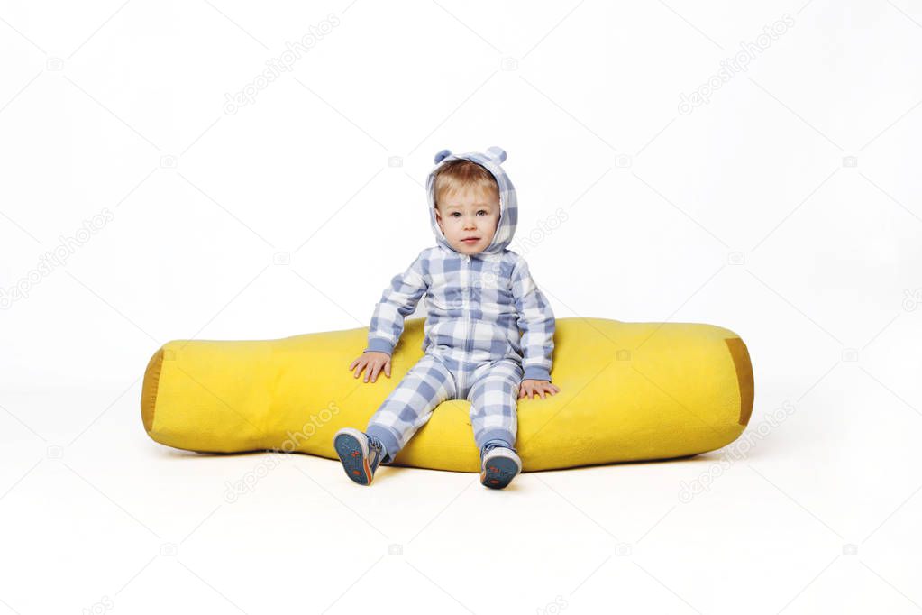 Portrait of an adorable baby boy sitting on the yellow bean bag.