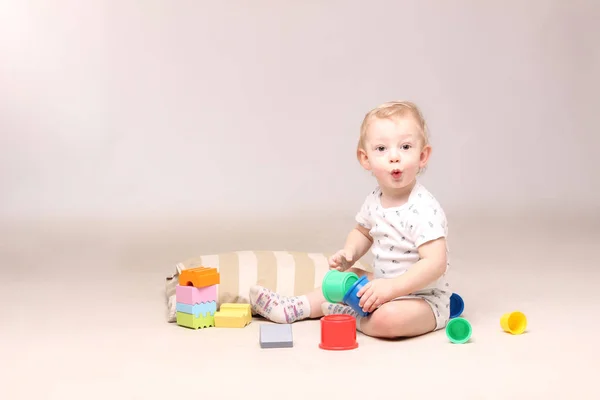 Surpris bébé garçon assis et jouer avec des jouets . — Photo