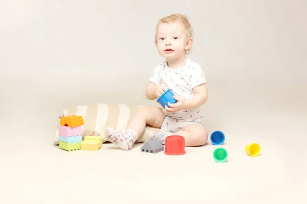 Entzückender kleiner Junge sitzt auf dem Boden und spielt mit einigen Spielzeugen. — Stockfoto