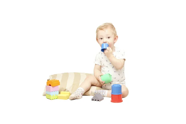 Petit garçon assis et jouer avec des jouets isolés sur fond blanc . — Photo