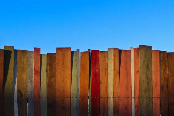 五彩木墙和蓝天 带有大量复制空间的彩色木墙 木栅栏和蓝天 彩绘老破旧的木桌背景 木制背景 — 图库照片